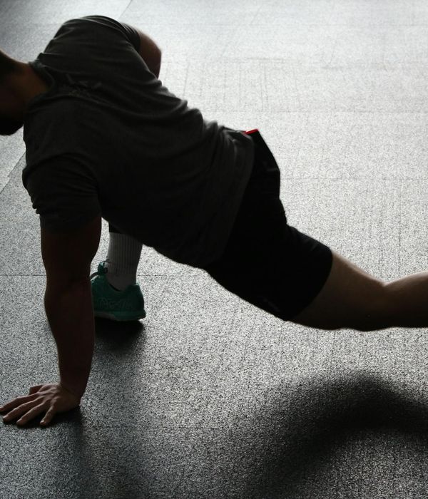 Man performing a core strength exercise in a dark room.